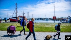 Tourists with backpacks and suitcases arrives at the port of Kloster on the Baltic island Hiddensee in Vitte, Germany, May 25, 2020. 