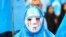 A person wearing a white mask with tears of blood takes part in a protest march of ethnic Uighurs during a demonstration around the EU institutions in Brussels.