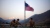 FILE - In this Sept. 11, 2011 photo, US soldiers sit beneath an American flag just raised to commemorate the tenth anniversary of the 9/11 attacks at Forward Operating Base Bostick in Kunar province, Afghanistan. 