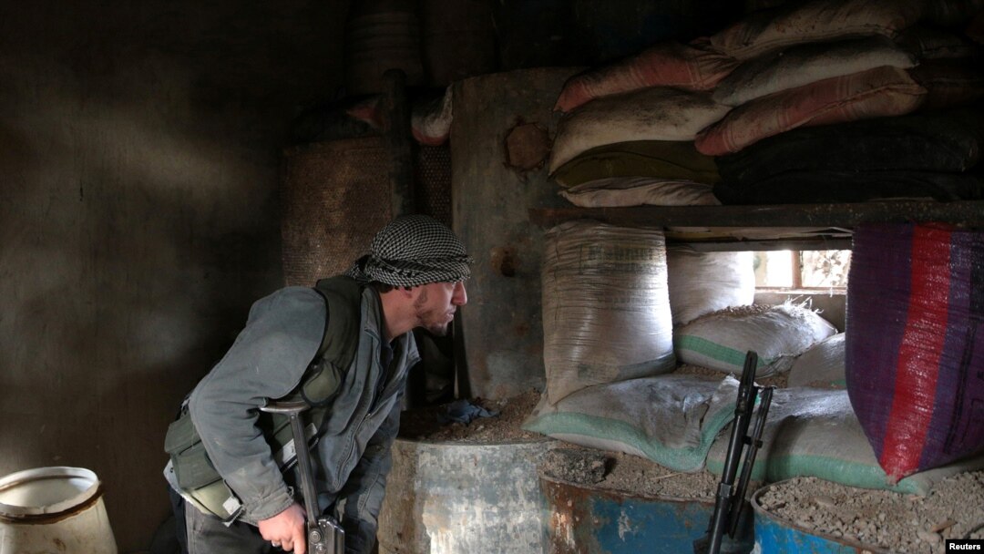 Seorang pejuang pemberontak terlihat dari belakang karung pasir, di hari keempat gencatan senjata, di desa al-Rayhan di dekat kota Douma, di bagian timur Damaskus pinggiran Ghouta, Suriah, 2 Januari 2017. (REUTERS/Bassam Khabieh)