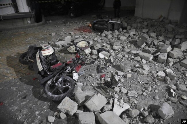 Sebuah sepeda motor yang rusak tertimpa dinding yang roboh akibat gempa bumi di Surabaya, Jawa Timur, Jumat, 22 Maret 2024. (Foto: Trisnadi/AP Photo)