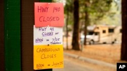 A sign warns departing campers of closures, July 25, 2018, in Yosemite National Park, Calif. Parts of the park closed Wednesday as firefighters work to contain the Ferguson Fire. 