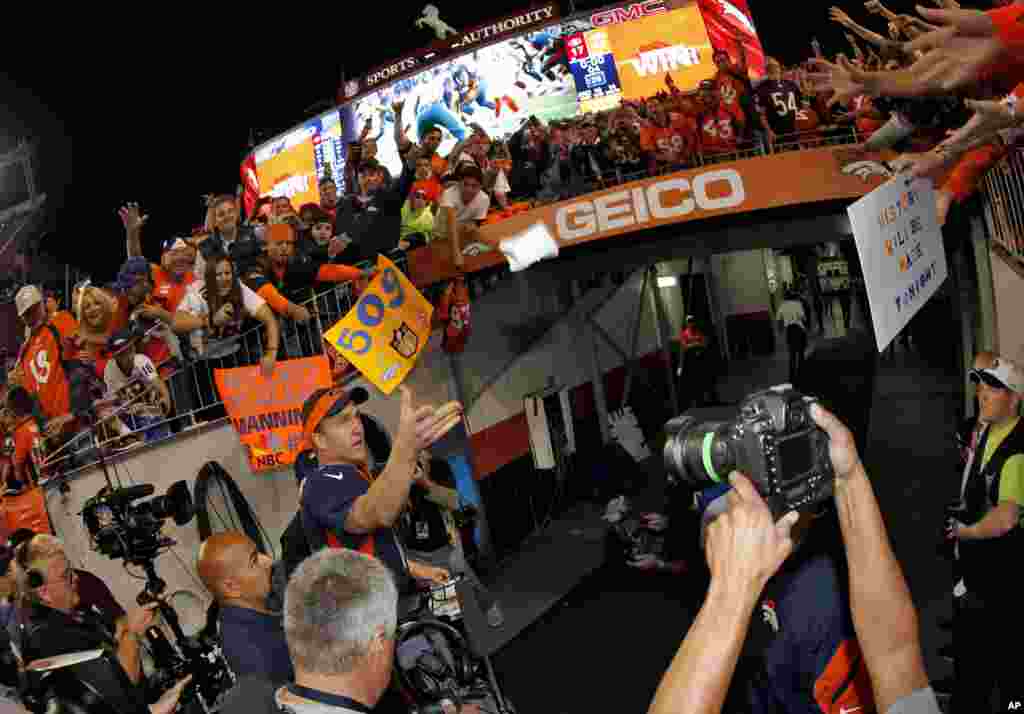 Denver Broncos quarterback Peyton Manning tosses his wrist bands to fans as he leaves the field in Denver, Oct. 19, 2014.