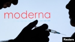 FILE - People pose with a syringe in front of a Moderna logo. Moderna, along with fellow pharmaceutical company Merck, announced Dec. 14, 2023, they had found success in reducing the chance of recurrence of melanoma by combining a Moderna vaccine with Merck's Keytruda.