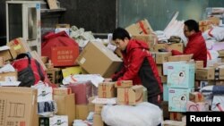 Deliverymen of JD.com work among parcels beside a road after the 11.11 Singles' Day shopping festival in downtown Beijing, Nov. 12, 2019.