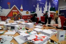 Postal workers who call themselves 'Elves' open envelopes addressed 'Pere Noel' -- Father Christmas in French - - decorated with love hearts, stickers and glitter, in Libourne, southwest France, Monday, Nov. 23, 2020.