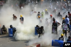 FILE - Protesters react after tear gas is fired by police during a demonstration against the military coup in the northwestern town of Kalay, March 2, 2021.