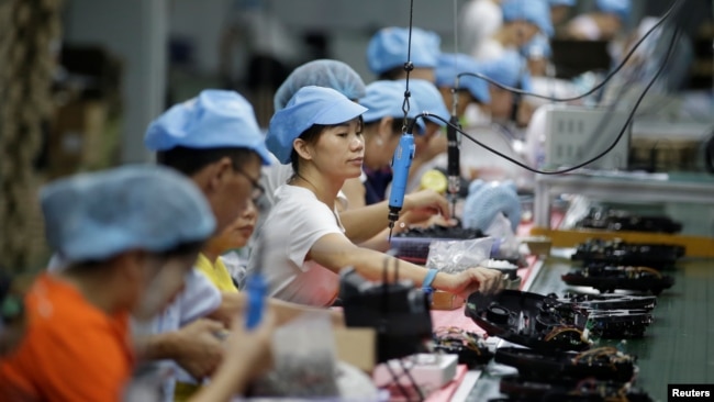 资料照:中国深圳一家工厂的工人在生产线上制造吸尘器。(2019年8月9日)
