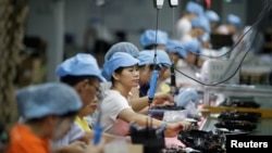 资料照：中国深圳一家工厂的工人在生产线上制造吸尘器。（2019年8月9日）