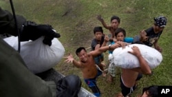 Villagers affected by last week's Typhoon Haiyan scramble for aid from a U.S. Navy Sea Hawk helicopter from the U.S. aircraft carrier USS George Washington in the coastal town of Tanawan, central Philippines, Nov. 17, 2013. 