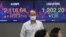 A currency trader passes by screens showing Korea Composite Stock Price Index (KOSPI), left, and foreign exchange rate at the foreign exchange dealing room of the KEB Hana Bank headquarters in Seoul, South Korea, July 2, 2020.