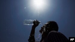 Seorang pria menuangkan air ke wajahnya pada suatu hari musim panas di Hyderabad, India. (Foto: AP)