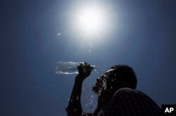 FILE - In this May 24, 2015 file photo, a man pours water on his face during a hot summer day in Hyderabad, India.