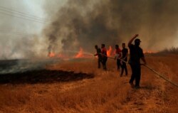 FILE - Iraqi farmers and other residents attempt to put out a fire that engulfed a wheat field in the northern town of Bashiqa, east of Mosul, Iraq, June 12, 2019.