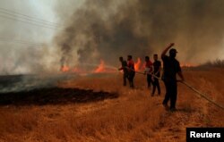 FILE - Iraqi farmers and other residents attempt to put out a fire that engulfed a wheat field in the northern town of Bashiqa, east of Mosul, Iraq, June 12, 2019.