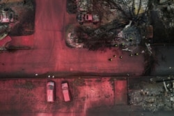 A search and rescue team, surrounded by red fire retardant, looks for victims under burned residences and vehicles in the aftermath of the Almeda fire in Talent, Oregon, Sept. 13, 2020.