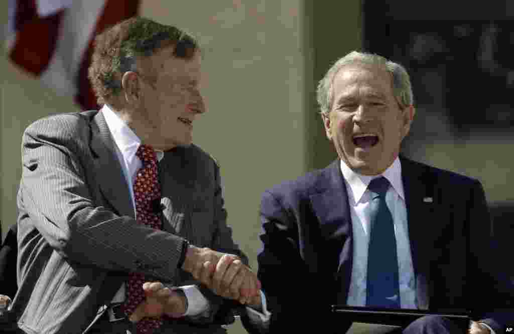 Mantan presiden George H.W. Bush berjabat tangan dengan anaknya, mantan presiden George W. Bush dalam peresmian Pusat Kepresidenan George W. Bush, Dallas, 25 April 2013.