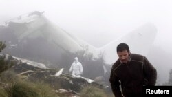 An investigator (back) works near the wreckage of a military plane which crashed near the village of Ouled Gacem in eastern Algeria, about 500km (311 miles) from the capital Algiers on February 12, 2014. The military transport plane carrying members of the Algerian armed forces and their relatives crashed into a mountain, killing 77 people, the worst air disaster in the North African country in a decade. (REUTERS/Louafi Larbi)