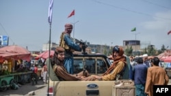 Taliban fighters on a pick-up truck move around a market area bustling with local shoppers, in Kabul, Afghanistan, Aug. 17, 2021, following the insurgent group's takeover of the country.