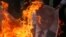 A Palestinian protester burns a poster depicting U.S. President Donald Trump during a protest against Trump's decision to recognize Jerusalem as the capital of Israel, in Gaza City, Dec. 7, 2017.