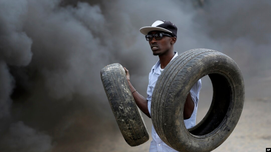 Un manifestant tient des pneus que son groupe utilise dans une barricade enflammée à Bujumbura, Burundi. jeudi 30 avril 2015