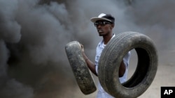 Un manifestant tient des pneus que son groupe utilise dans une barricade enflammée à Bujumbura, Burundi. jeudi 30 avril 2015