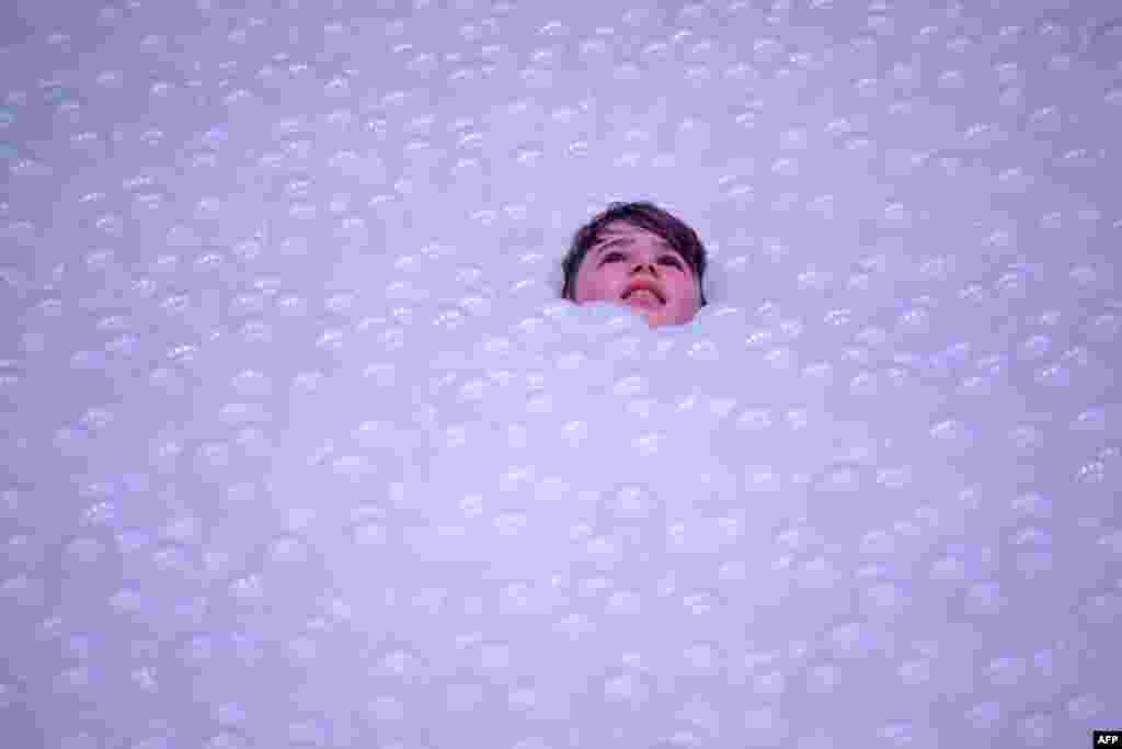 A child plays in an art installation called The Beach as they &quot;float&quot; on polyethylene balls as part of the annual Sydney Festival, Australia. The Beach at The Cutaway, Barangaroo Reserve, comprises 1.1 million recyclable polyethylene balls that create an ocean gently lapping against a 60-meter-wide shoreline free of sand created by New York-based design studio Snarkitecture.