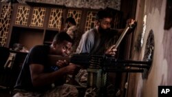 FILE -- In this Sept. 27, 2016 file photo, a Libyan fighter affiliated with the Tripoli government searches for sniper positions from a hole in a building on the frontline with Islamic State militants, in Sirte, Libya.