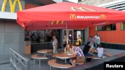 People sit outside a closed McDonald's restaurant in Moscow, Aug. 20, 2014.