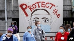 Health care workers and other staff gather at a distance at Harborview Medical Center in a demonstration asking management to do more to protect staff, patients and the public amid the COVID-19 pandemic, May 14, 2020, in Seattle.