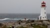 Two Royal Canadian Mounted Police officers walk toward the Peggy's Cove Lighthouse to warn individuals of the dangers during the arrival of Hurricane Dorian in Peggy's Cove, Nova Scotia, Sept. 7, 2019.