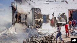 Orang-orang membersihkan puing-puing di lokasi ledakan bom di Mogadishu, Somalia, 12 Januari 2022. (AP/Farah Abdi Warsameh)