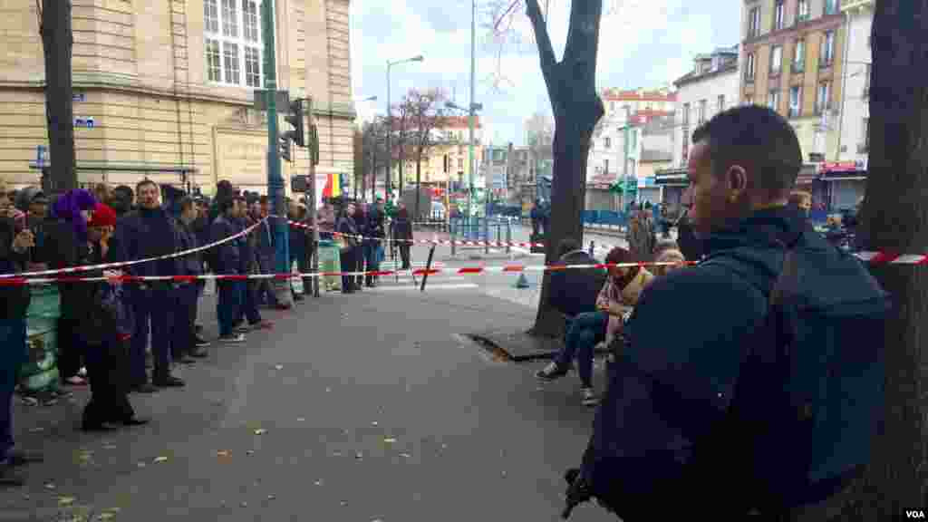 Une foule regarde la police déployée lors de l&rsquo;assaut contre des personnes présumées liées aux attaques meurtrières dans la capitale française, à Saint-Denis.