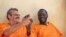 FILE - James Gatdet Dak, right, clasps hands with William Endley, left, a South African former defense colonel who also worked with the opposition, as they prepare to be released from prison after their death sentence was pardoned, in Juba, South Sudan, Friday, Nov. 2, 2018. 