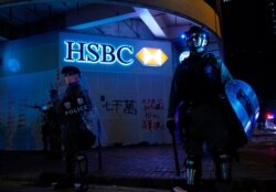Police stand guard in front of a vandalized HSBC bank on New Year's Day in Hong Kong, Jan. 1, 2020.