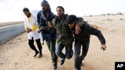 ກຳລັງຕໍ່ຕ້ານລັດຖະບານໃນລີເບຍ ຊ່ອຍເພື່ອນທີ່ໄດ້ຮັບບາດເຈັບ ໃນລະຫວ່າງການປະທະກັນ ໃກ້ໆເມືອງ Ras Lanuf (9 ມີນາ 2011)