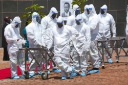 Pallbearers wait for coffins to arrive at a state burial of government ministers who died of COVID-19, in Harare, Zimbabwe, Jan. 21, 2021.