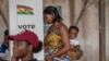 A woman with her child prepares her ballot in the general elections in Accra, Ghana, Dec. 7, 2024.