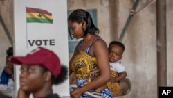 A woman with her child prepares her ballot in the general elections in Accra, Ghana, Dec. 7, 2024.