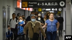 Pasajeros en el Aeropuerto Internacional San Oscar Romero en San Luis Talpa, El Salvador, usan mascarillas como precaución contra la propagación del COVID-19, el 12 de marzo de 2020.