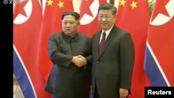 Poignée de main ferme entre le leader nord-coréen Kim Jong Un et le président chinois Xi Jinping, Beijing, le 28 mars 2018 (CCTV)