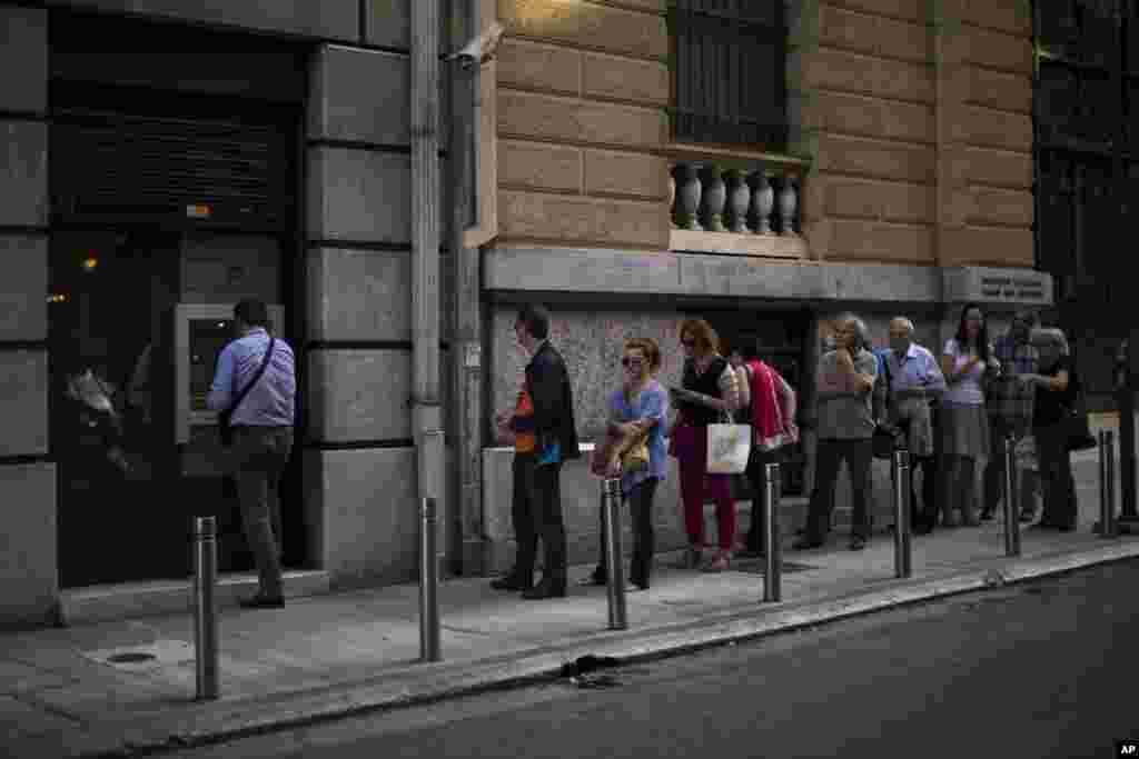 People line up to withdraw money from a bank machine in central Athens, July 3, 2015.