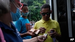 Personas pagan el pasaje del autobús con un puñado de billetes de Bolívar, la moneda oficial del país, en Caracas, el 5 de agosto de 2021.