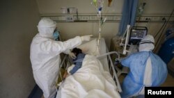 Medical workers in protective suits attend to a patient inside an isolated ward of Wuhan Red Cross Hospital in Wuhan, the epicenter of the novel coronavirus outbreak, in Hubei province, China, Feb. 16, 2020. (Credit: China Daily)