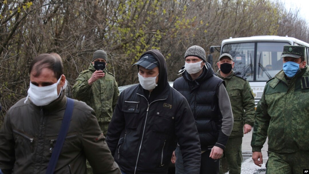 Ukrainian war prisoners, escorted by Russia-backed separatist soldiers, all wearing face masks to protect against coronavirus, walk to be exchanged near a checkpoint in Horlivka, eastern Ukraine, April 16, 2020. 