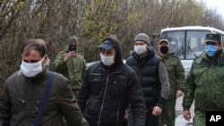 Ukrainian war prisoners, escorted by Russia-backed separatist soldiers, all wearing face masks to protect against coronavirus, walk to be exchanged near a checkpoint in Horlivka, eastern Ukraine, April 16, 2020. 