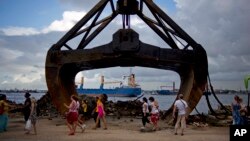 FILE - Tourists walk past an excavator shovel at the harbor of Havana, Cuba,Aug. 20, 2013. 