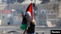 Un joven palestino sostiene una bandera durante enfrentamientos entre manifestantes palestinos y la policía israelí.