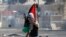 Un joven palestino sostiene una bandera durante enfrentamientos entre manifestantes palestinos y la policía israelí.