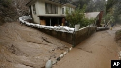 Une coulée de boue longe une maison protégée par des sacs de sable à Monrovia, en Californie, 6 janvier 2016. 